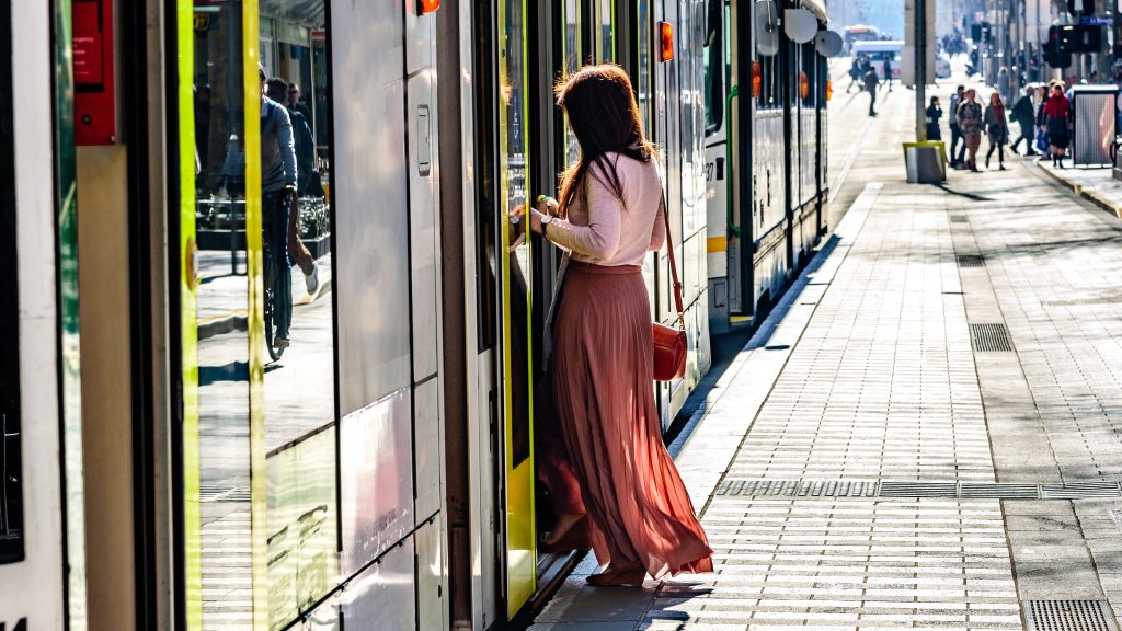 An unidentified female with a long dress is getting onboard a Melbourne Australia city tram in the central business district
