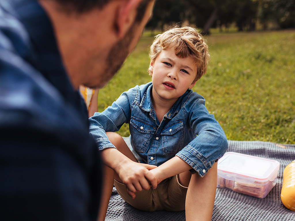 Young boy having a picnic in the sun with his dad.